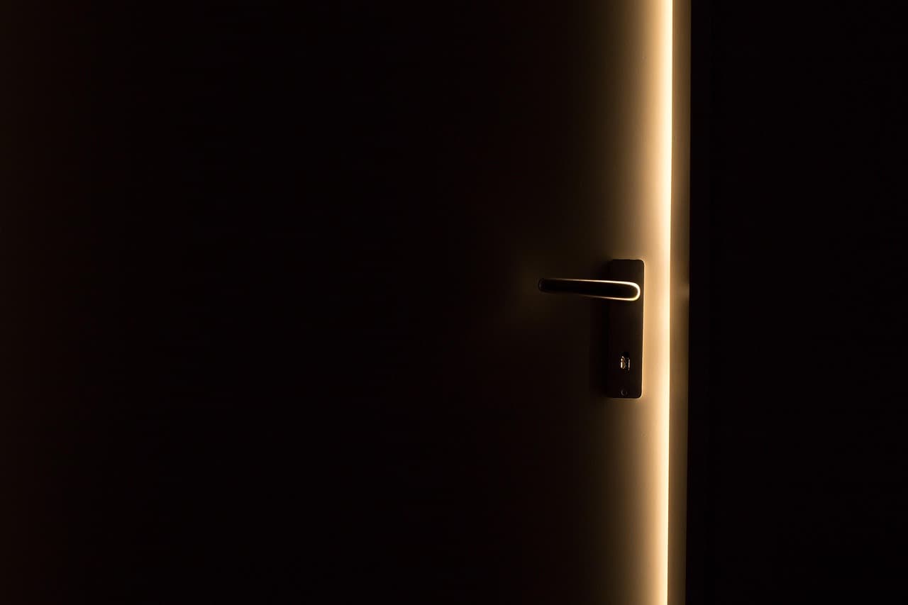 A door left ajar in the dark, light from the hall falling through