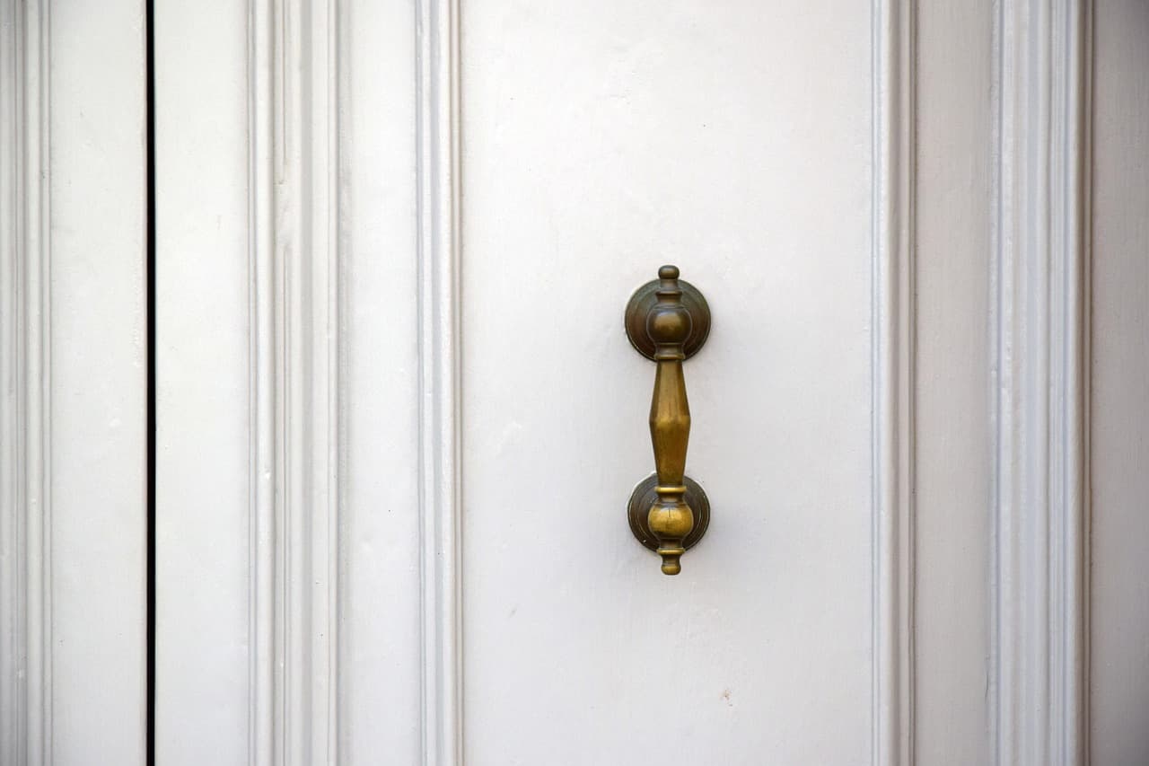A white panelled door with a brass handle